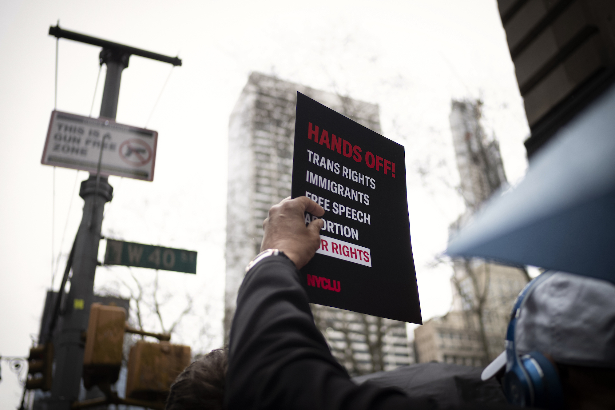 A demonstrator holding a sign from the ACLU of New York.