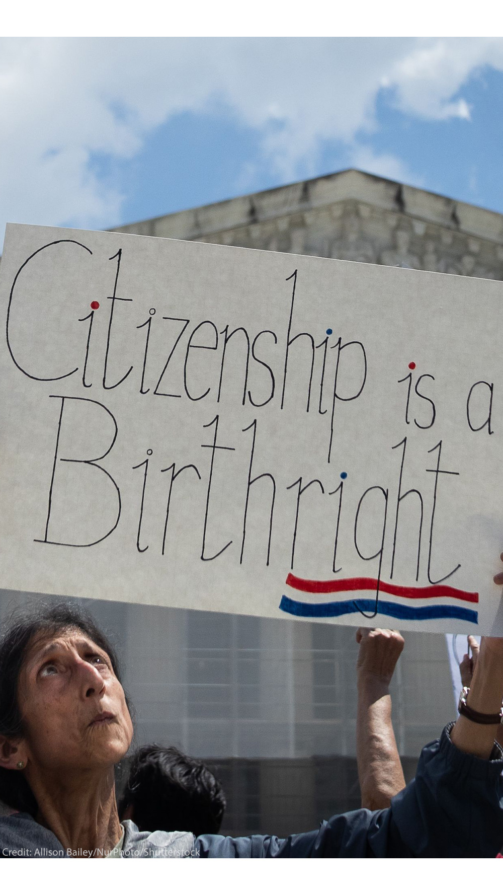 A demonstrator looks up at her sign (which reads "Citizenship is a Birthright") during a rally outside the Supreme court building demanding the court uphold the 14th Amendment to the U.S. Constitution.