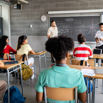 A student presenting in front of a diverse classroom.
