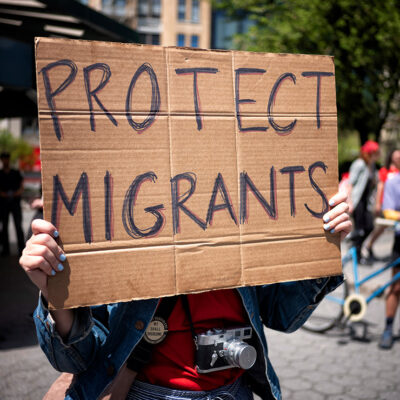 A demonstrator holding a sign that says "Protect Immigrants."