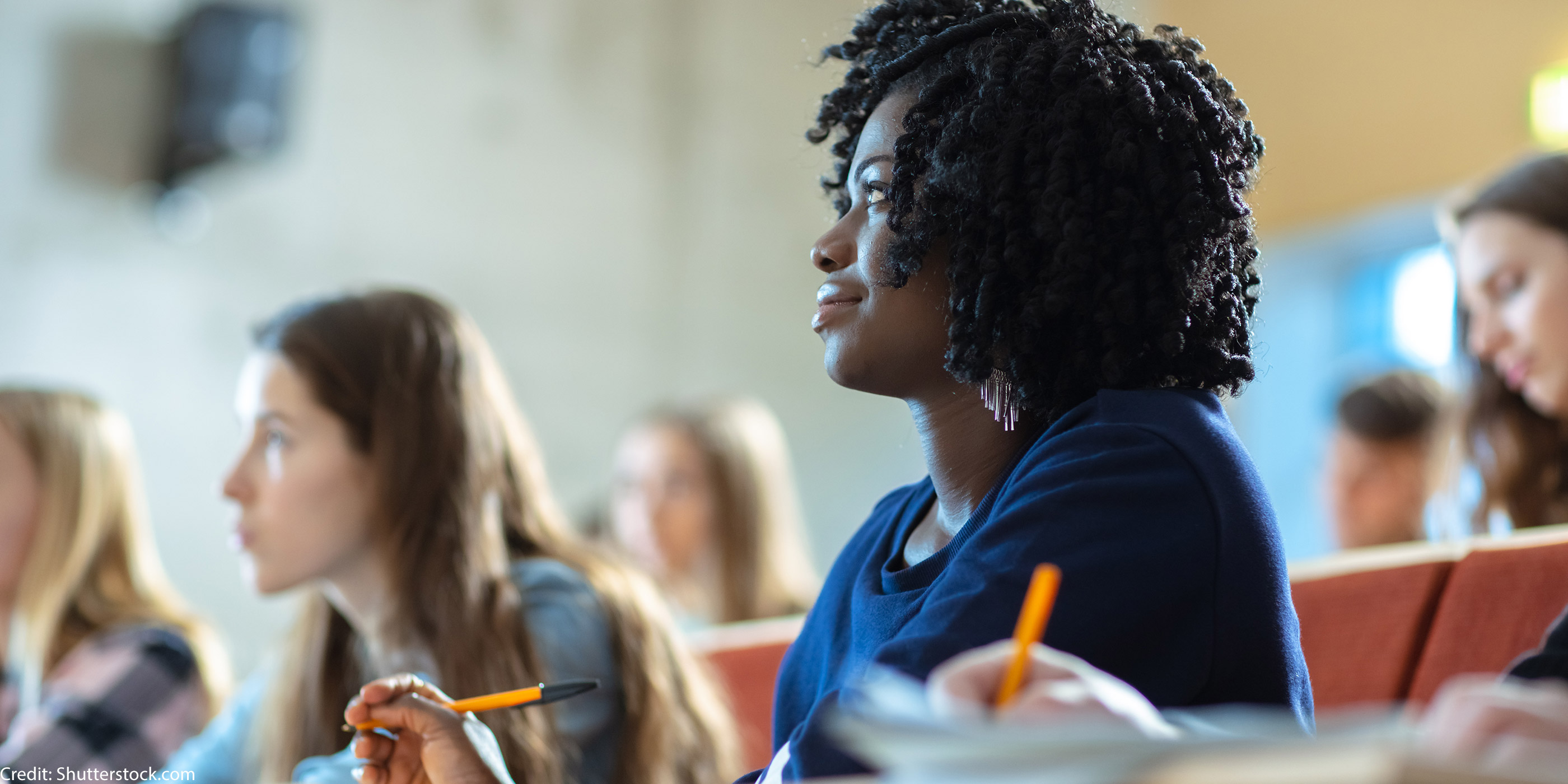A woman in a classroom taking notes.