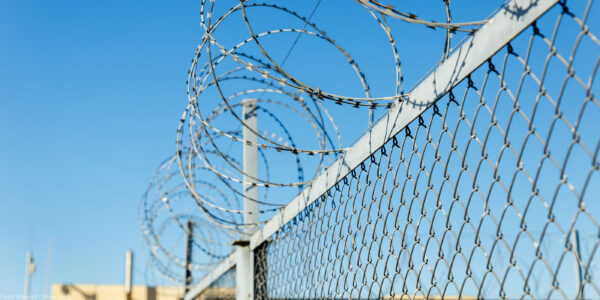 A chain link fence with razor wire running along the top.