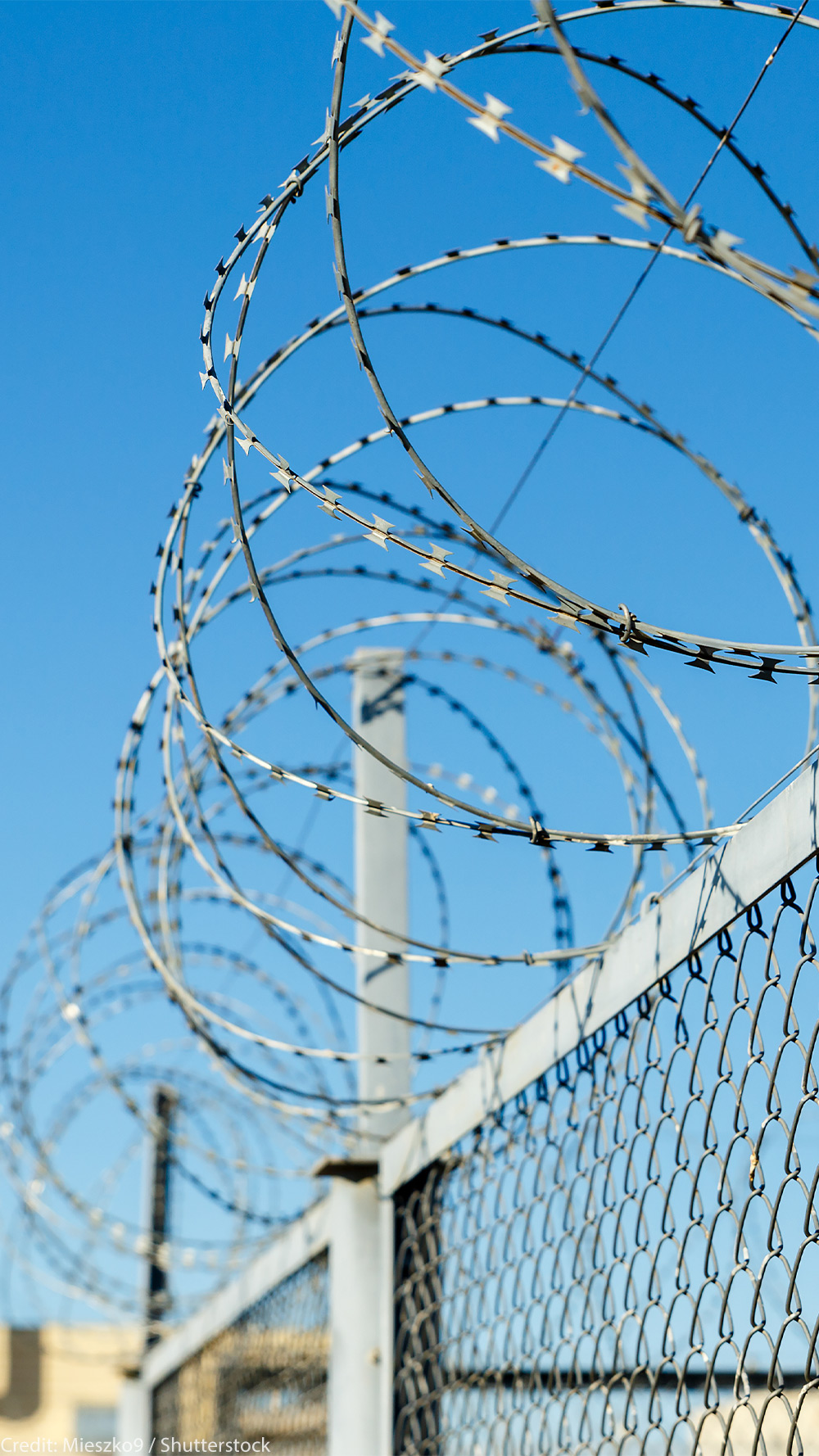 A chain link fence with razor wire running along the top.